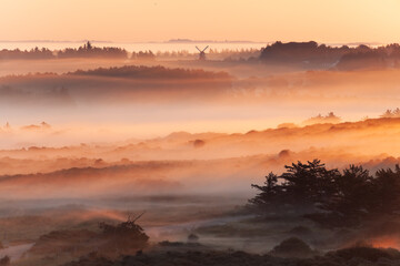 Beautiful sunrise at Lighthouse of Rubjerg Knude. Denmark north coast with wonderfully illuminated fog.