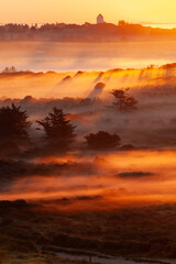 Beautiful sunrise at Lighthouse of Rubjerg Knude. Denmark north coast with wonderfully illuminated fog.