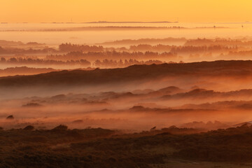 Tower lookout with beautiful sunrise at Lighthouse of Rubjerg Knude. Denmark north coast with wonderfully illuminated fog.