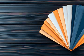 Color palette samples fanned on dark wood background, design concept.