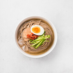 Naengmyeon, Korean cold noodles in a white ceramic bowl. Traditional Asian food, top view