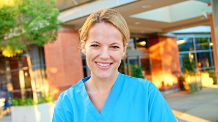 Portrait Of Female Doctor Or Nurse Wearing Scrubs At Work Standing Outside Modern Hospital