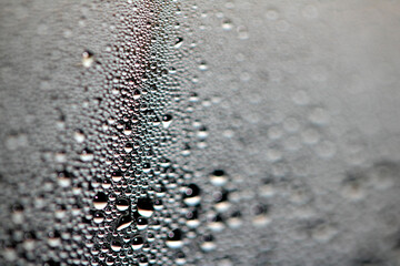 Close Up of Condensation Floating Liquid Water Bubbles and Drips on Glass from Rain