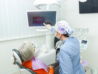 Dentist showing radiography to senior patient in dental clinic