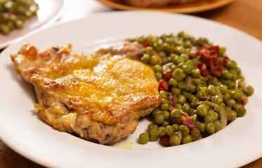 Fried boneless skinless chicken leg with green peas for garnish on plate