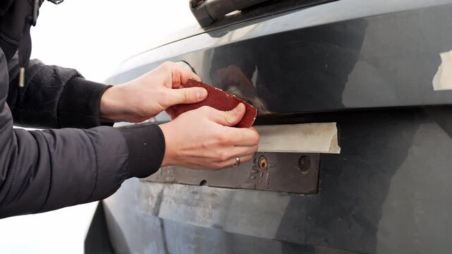 Male hands remove rust from the trunk, back door of a car, vehicle with sand paper, car service repair, old and new, static close up, white background