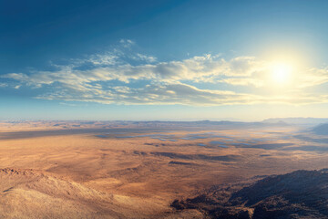 Naklejka premium Vast desert landscape with solar panels under a bright sun and scattered clouds.