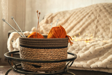 Basket full of red thread spools against sofa and warm blanket. Creative and warm atmosphere
