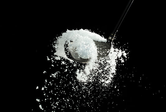 Golf Ball golfer hit snow to explode and splatter. Sand wedge golf dick ball from snow field and snow fly in air. Night black background isolated