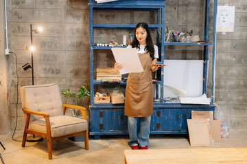 Cheerful female artist painting in a vibrant studio with brushes, a palette, and a blank canvas.