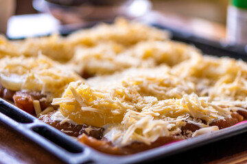 Fried chicken fillet with pineapple and cheese on a dark baking sheet