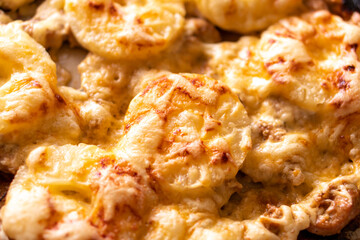 Fried chicken fillet with pineapple and cheese on a dark baking sheet