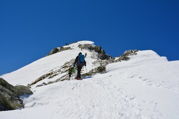 雪の唐松岳山頂直下を登る登山者