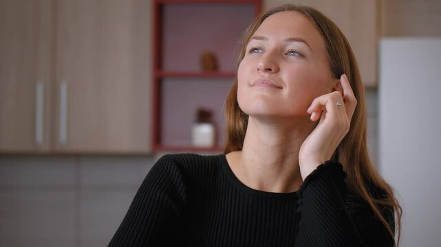 Young woman leans on her kitchen counter, resting her chin on her hand while lost in deep thought. Moment of tranquility fills space as she enjoys peaceful, contemplative break