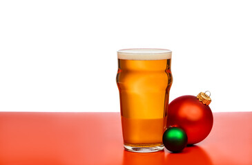 A pint glass of beer with festive Christmas baubles on a red and white background