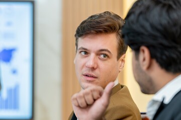 A man in a brown coat is talking to another man in a black suit.