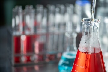 Image shows a close up of a chemistry experiment with a boiling flask containing a red liquid and a thermometer.
