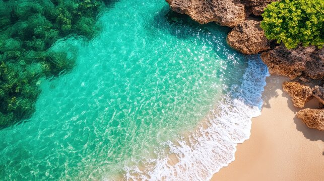 Turquoise waters lap gently against a golden sandy beach, bordered by rocky outcrops and lush greenery, creating a tropical and inviting seascape.