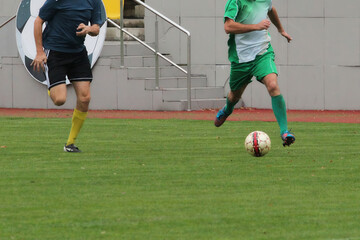 Soccer players on a football field during a match, footballers running after the ball across the...