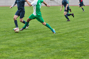 An attacker and a defender from football teams are fighting for the ball on the football field, an attacking soccer player with the ball against a defender