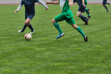 Fototapeta premium Football players with the ball on the football field. Footballers in action at a tournament game. Adult soccer competition close-up.