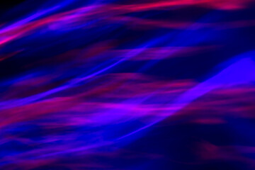 Defocused abstract red, pink and blue background of speed camera movement over glowing lights. A pattern of flashes of light similar to the northern lights