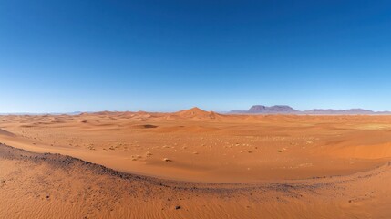 Naklejka premium A vast, empty desert with endless sand dunes stretching to the horizon under a clear blue sky