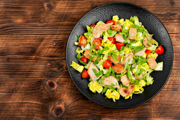 Meat salad with vegetables on wooden table.