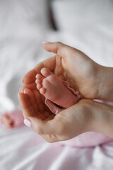 A baby's foot is being held in a mother's hand. The baby is wearing pink clothing