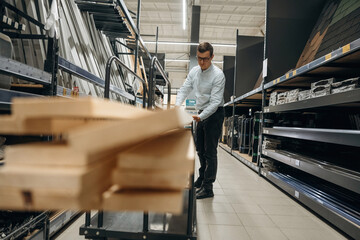 Wooden planks. Male hardware store worker in indoors