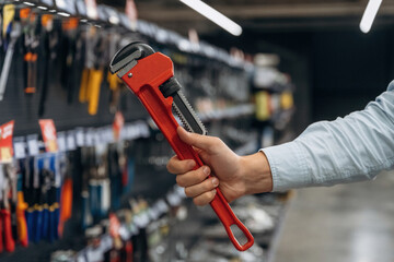 Fototapeta premium Pіре wrench in hands. Detailed close up view of man's hand in the hardware store