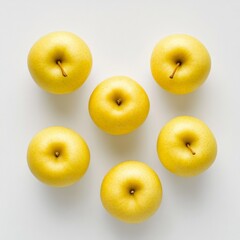 Golden apples arranged in a neat layout on a white surface showcasing their smooth texture and vibrant color
