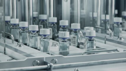 Close-up of Medical Glass Vials with White Caps on Conveyor Line at Modern Pharmaceutical Factory. Medicine Manufacturing Process. Medicinal Drug Production Plant. 