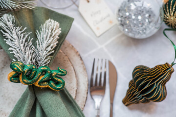 Stylish plates, napkin, glass, champagne, Christmas tree branches and Christmas decorations on a gray background. Table setting. The concept of Merry Christmas and New Year 2025.