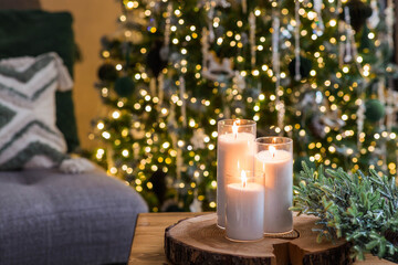 Christmas Eve. A candle on the table in the living room and a fir wreath. New Year's decor in the interior. The concept of preparing the house for Christmas and New year.