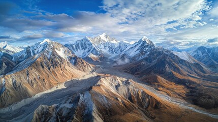 Drone perspective of a mountain range, with snow-capped peaks and valleys beneath
