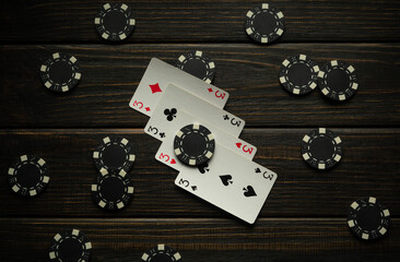 Win at poker with a lucky combination of four of a kind or quads. Chips and cards on a black...