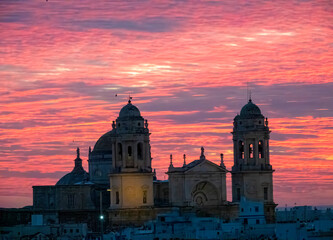 Obraz premium Colorful skies at dusk over the skyline of the old city of Cadiz featuring the silhouette of its famous cathedral, Cadiz, Andalusia, Spain