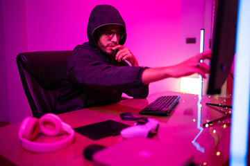 Black Hat Hacker hoodie concept at a laptop computer hacking the Internet. Cyber crime and security principles.