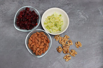 Ingredients for making cookies on a table. Top view photo of raisins, nuts and dried cranberries on a gray background with space for text. Healthy eating concept. 