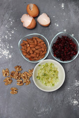 Ingredients for making cookies on a table. Top view photo of raisins, nuts and dried cranberries on a gray background with space for text. Healthy eating concept. 