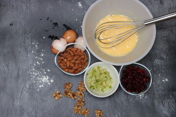 Ingredients for making cranberry pie - eggs, flour, sugar, nuts, raisins on a gray background