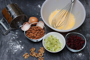 Ingredients for making cookies on a table. Top view photo of raisins, nuts and dried cranberries on a gray background with space for text. Healthy eating concept. 