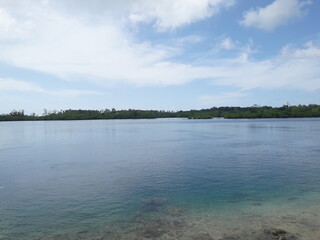Aceh Beach during the day, showing a beautiful view between the beach, sand, land, and sky. Aceh Beach is located on Simeulu Island, Sinabang- Indonesia.