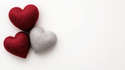 Fototapeta premium Three felted wool hearts in red and grey arranged on a clean white background with copy space.