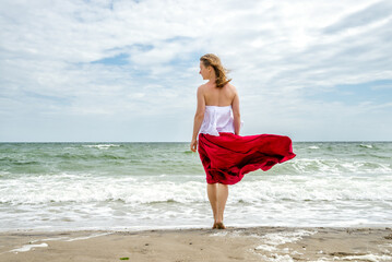 Beautiful girl in red dress by the sea.