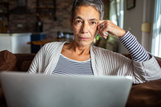 Senior woman relaxing on the couch with laptop at home