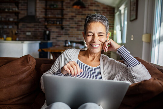 Senior woman relaxing on the couch with laptop at home