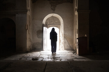 Silhouette of woman on the threshold of an ancient monastery. Black outline of a woman in a church....