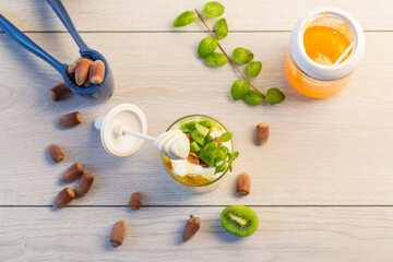 homemade yogurt with kiwi, honey and nuts in a glass on a wooden table